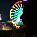 a person standing in front of a ferris wheel at night