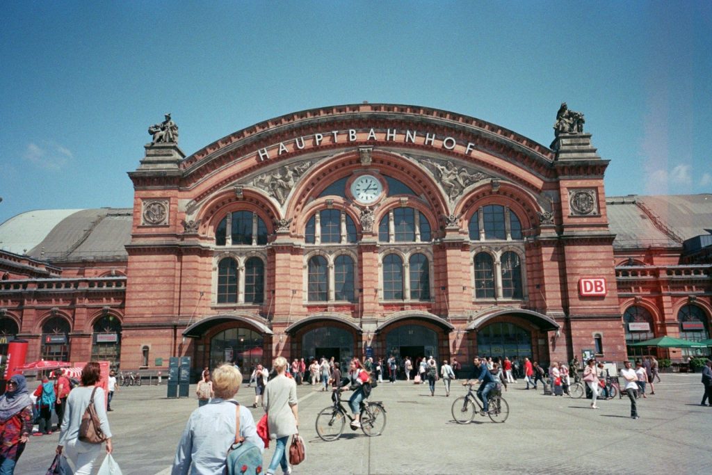 People walking and cycling in front of a large building