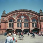 People walking and cycling in front of a large building
